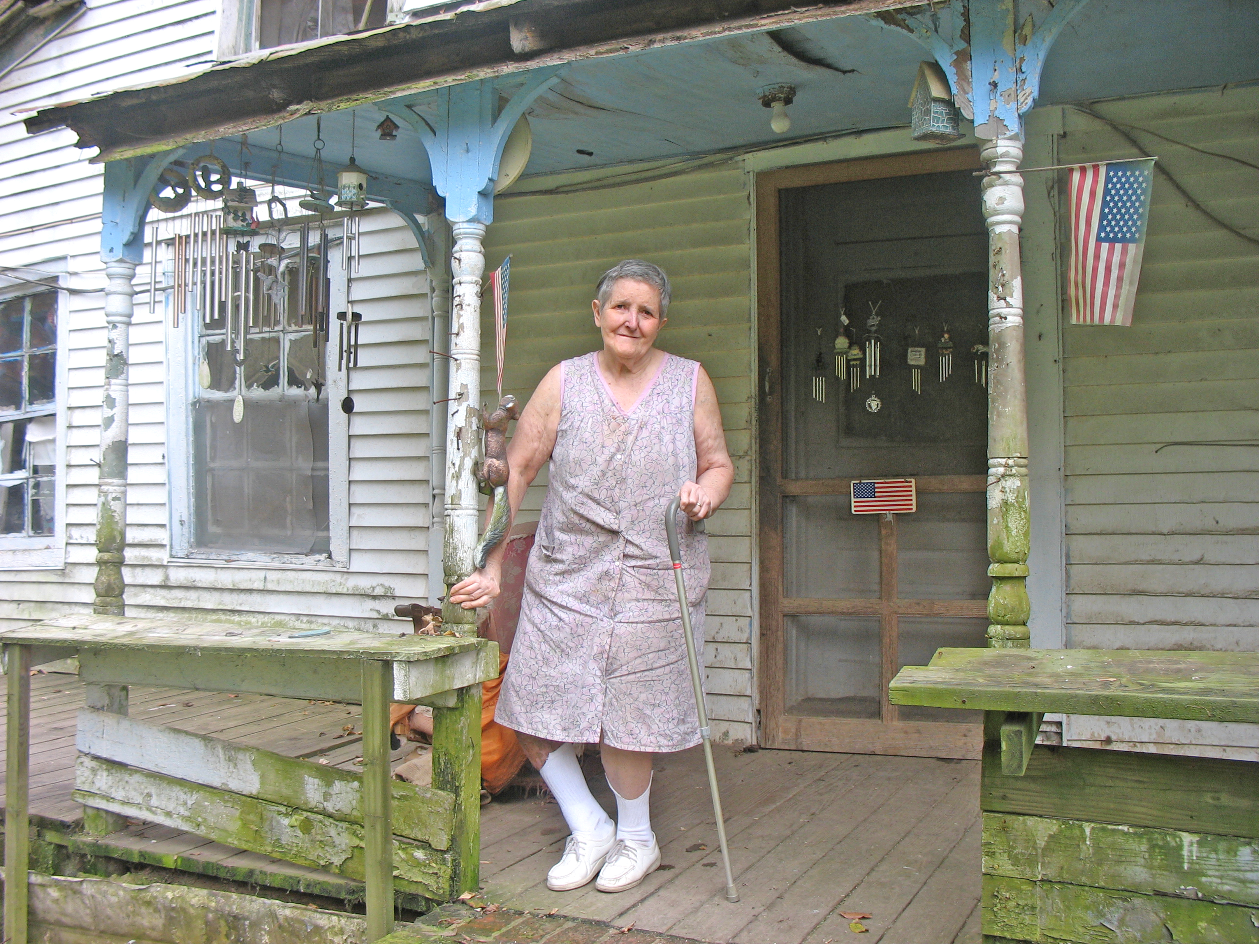 A woman stands outside a house.